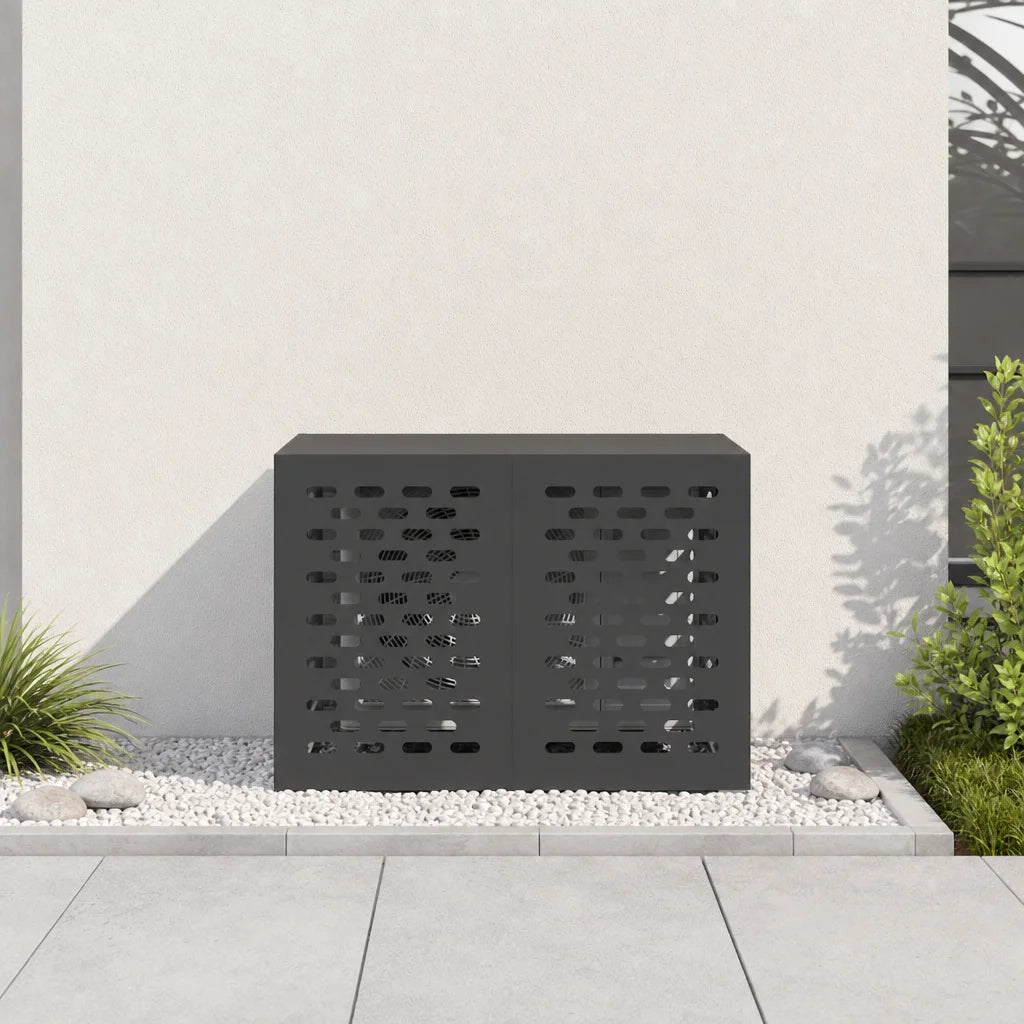 Cache clim extérieur noir installé contre une façade, entouré de plantes
